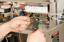 wires from an electrical box with a pair of hands snipping wires with wire snippers.
