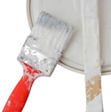 a paint bucket with a brush and stir stick